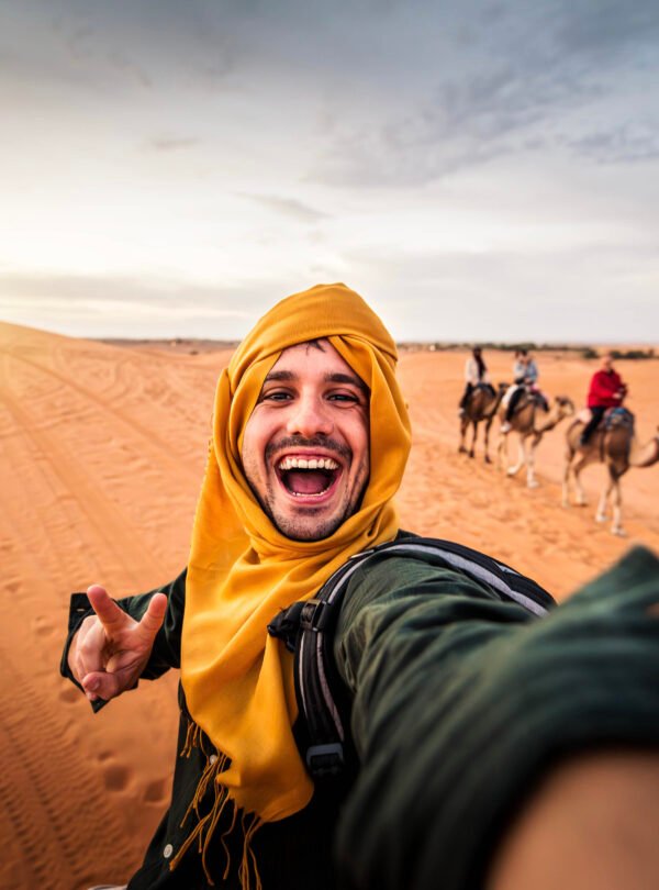 Happy tourist having fun enjoying group camel ride tour in the d
